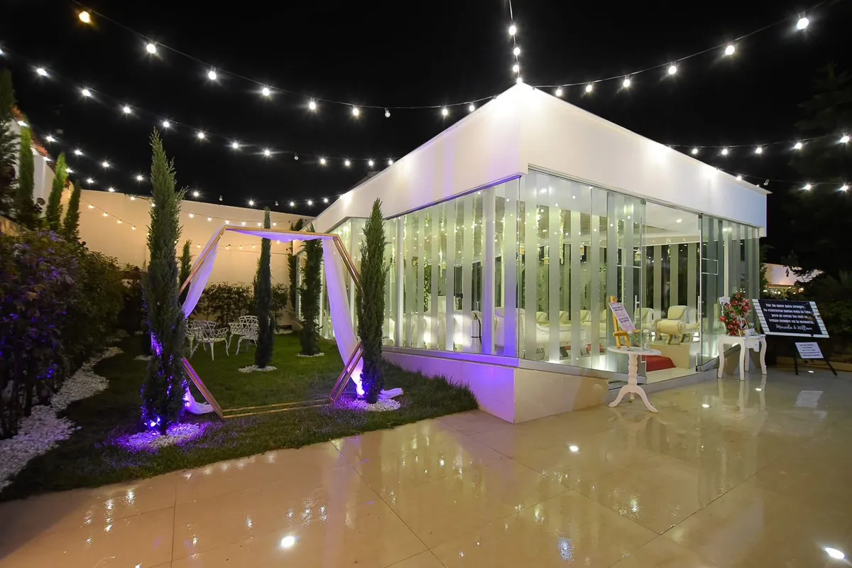 Capilla de cristal iluminada con arco floral para la ceremonia de una boda