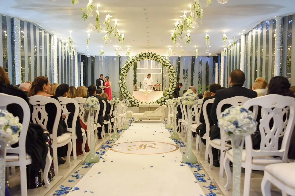 Sillas blancas decoradas con flores en el pasillo de una ceremonia de boda