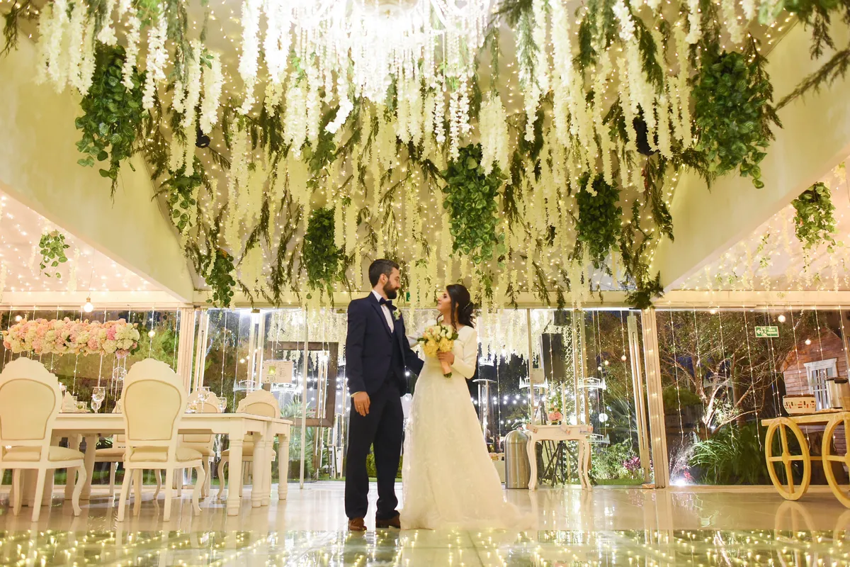 Pareja de novios en un salón decorado con flores colgantes