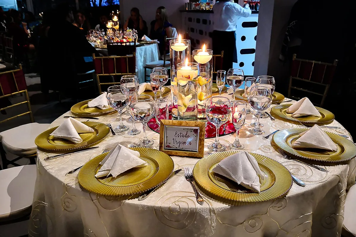 Mesa elegante con velas flotantes y vajilla dorada para una fiesta de quince