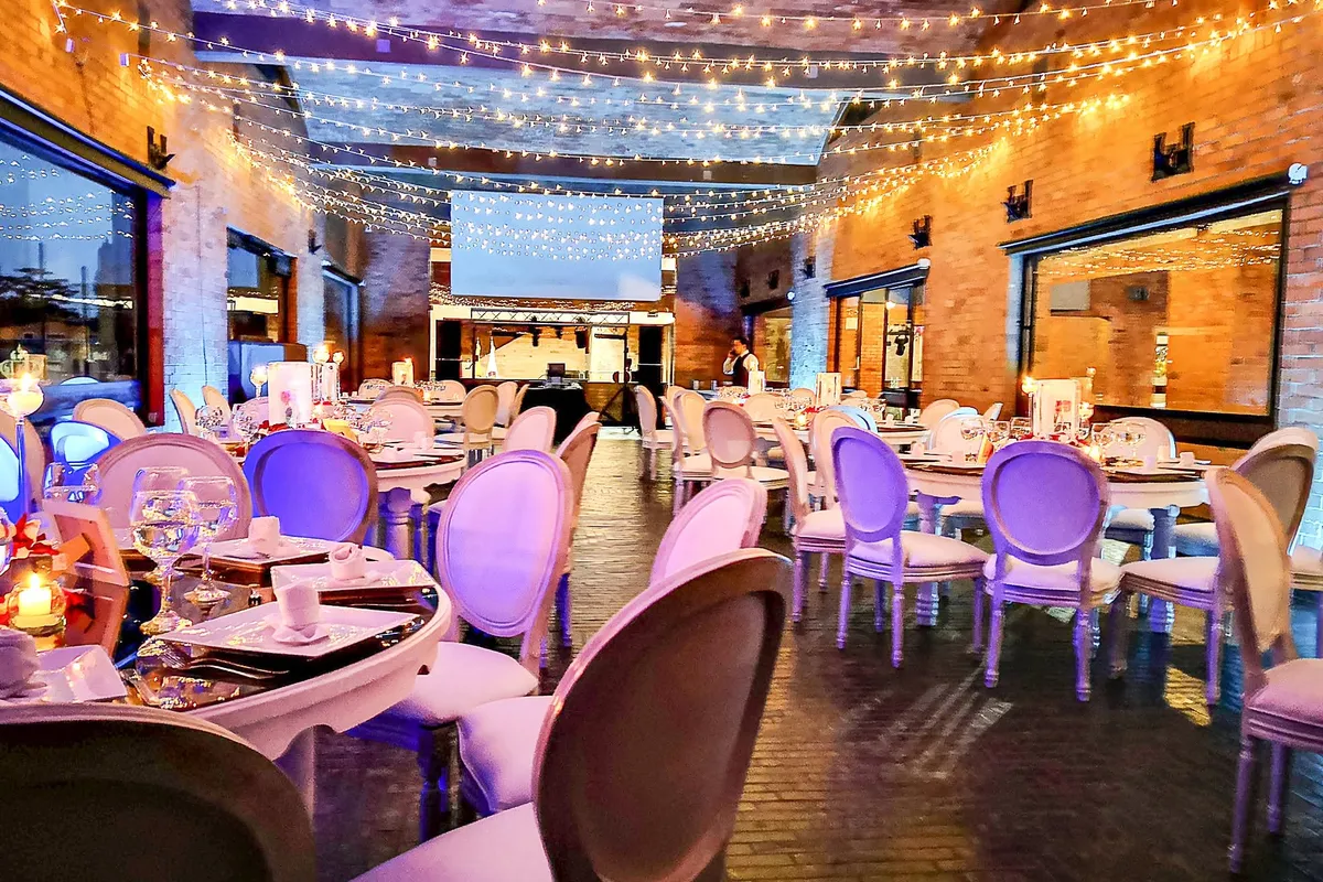 Salón decorado con luces cálidas y mesas para una fiesta de quince